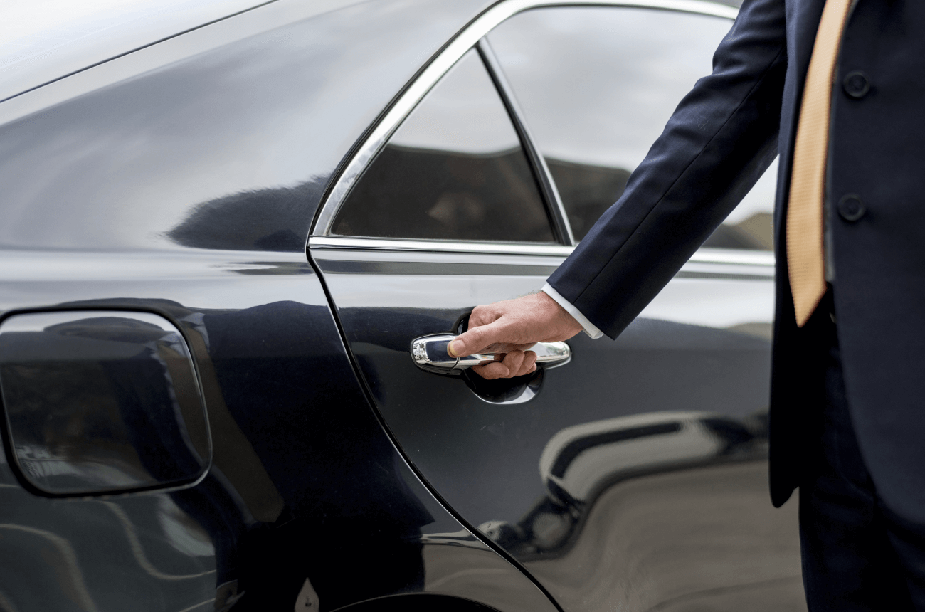 Luxury chauffeur car and professional driver opening car door for client.