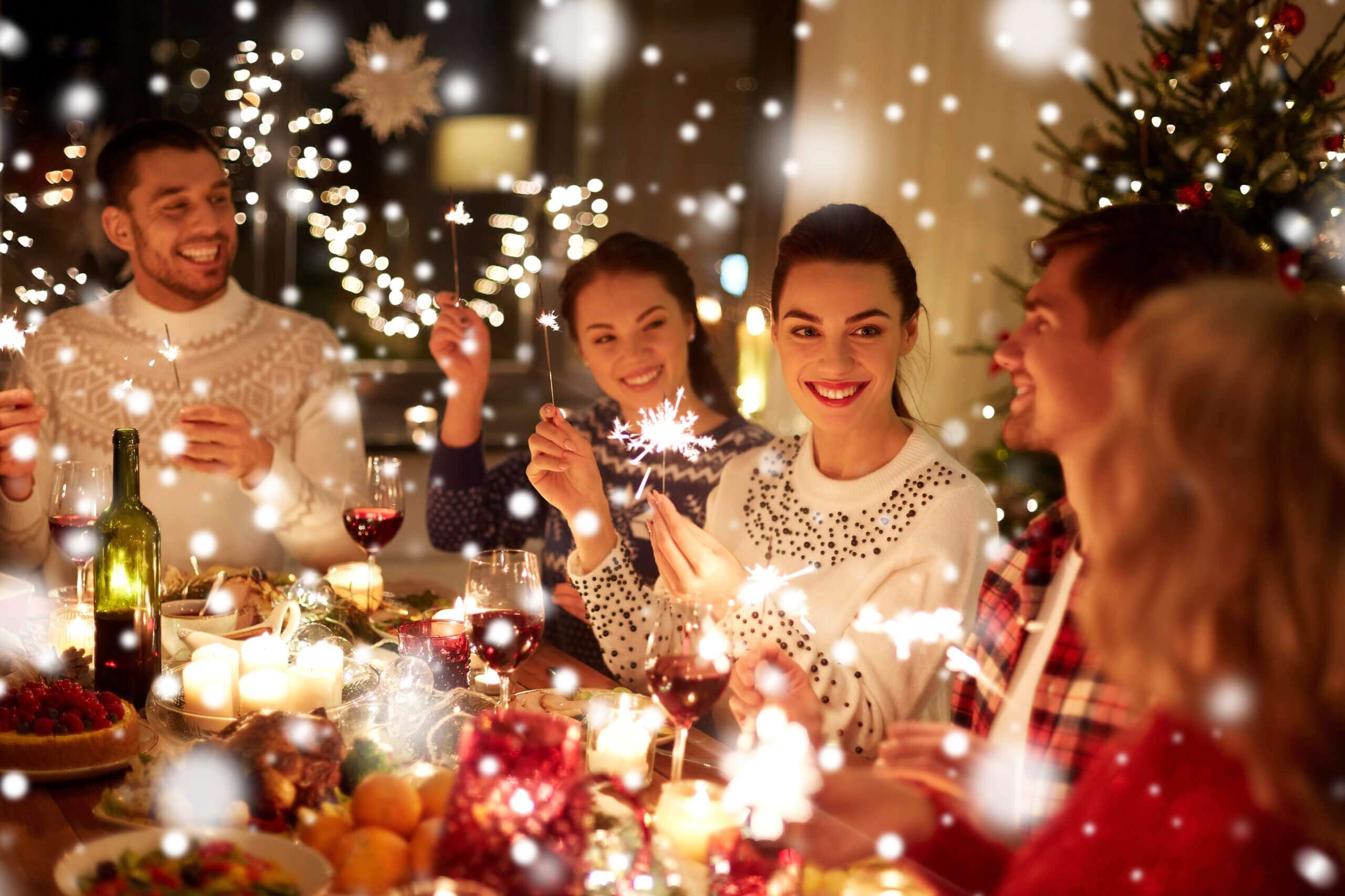 Group of friends celebrating Christmas with sparklers and festive decorations.