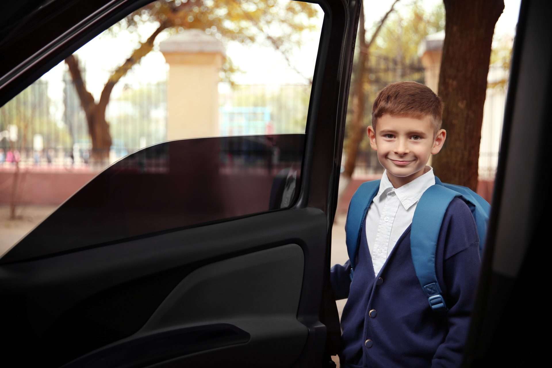 Schoolboy stepping into a luxury car for a safe school transfer.